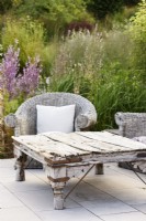 Old wooden table with wicker seating in a July garden