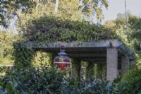 A colourful glazed urn stands in between a hedge and a large pergola in the Parque de Maria Luisa, Seville, Spain. September