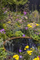 A large corten water bowl surrounded by dense plantings of flowering perennials: Achillea 'Moonshine' and Lychnis flos-cuculi 'Petite Jenny', Alchemilla mollis. Plants reflect in the water. Designer: Robert Moore