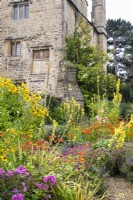 Summer flowering perennials including crocosmia, phlox, verbascum and helenium grouped alongside the manor house at The Manor, Little Compton.