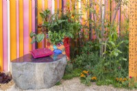 A stone bench, a painted old oil barrel planted with vegetables, herbs and flowers and perennial bed. The RHS and Eastern Eye Garden of Unity, Designer: Manoj Malde