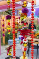  Marigold Garlands made of flowers, chilli peppers, fruits, woolly pom-poms and bracelets. The RHS and Eastern Eye Garden of Unity, Designer: Manoj Malde.