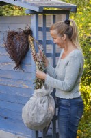 A woman hangs up to dry a lettuce seed head covered with a fleece bag.