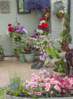 Cottage entrance with hanging baskets and containers of summer bedding plants