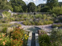Rill and pond in summer walled garden, informal planting of drought tolerant plants in gravel