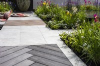 A pavement in a modern garden made of mixed materials and surrounded by a perennial beds. Designer: Kevin Dennis, Bord Bia Bloom 2023