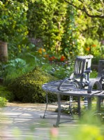 A metal tree seat in the Savills Garden, Designer: Mark Gregory, RHS Chelsea Flower Show 2023, May, Spring, Summer