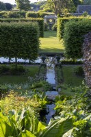 View down across formal rill, with clipped hedging and a view towards the wooden pergola.