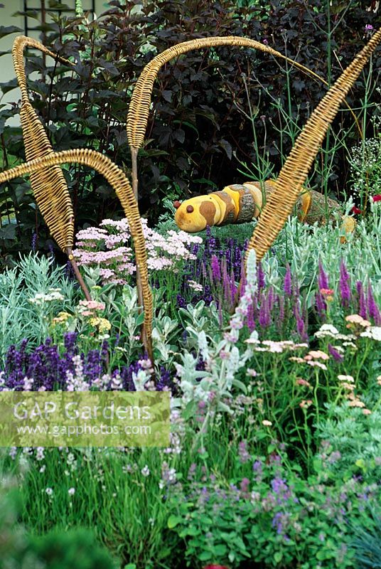 Ornaments in herbaceous purple border. Carved caterpillar and woven leaf sculptures