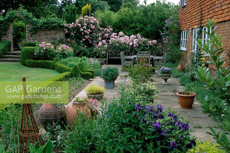 Patio in front of house with containers and furniture. Cacketts Farmhouse in Kent