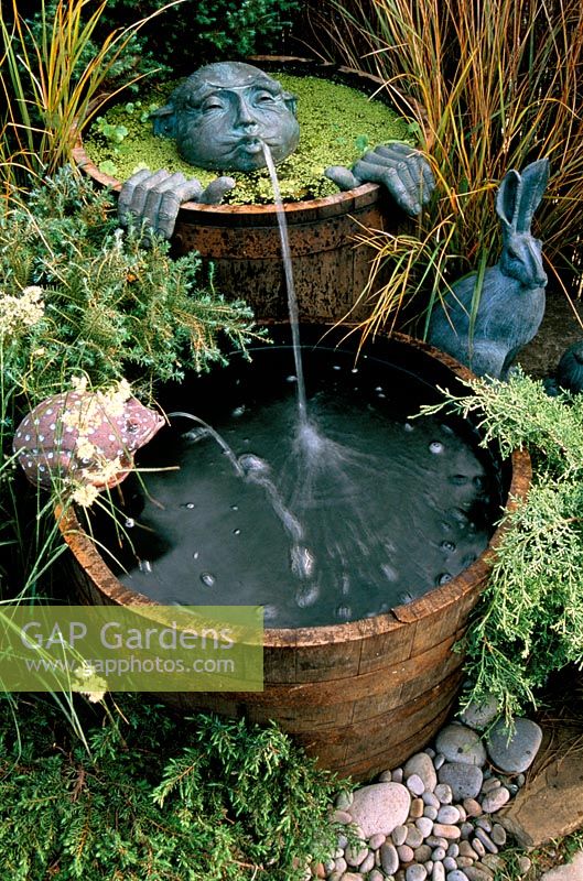Spitting man water feature in wooden barrels