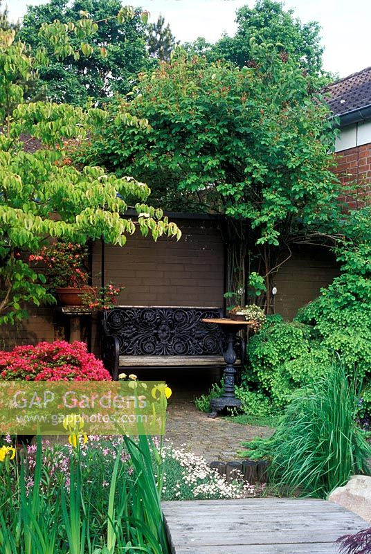 Small courtyard garden with bench and table. 