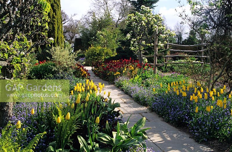 Spring garden with borders along path at Great Dixter in Sussex
