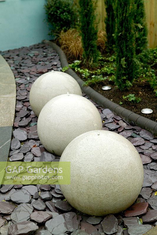 Row of three spherical water features in contemporary garden at Capel Manor Show Gardens