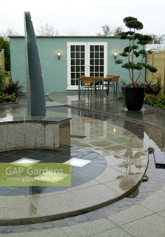 Modern garden with circular water feature and polished paving, Capel Manor Show Gardens
