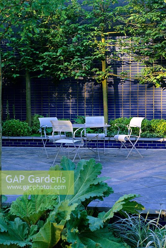 Cartier garden at Chelsea 2000, furniture on patio edged with structural green planting