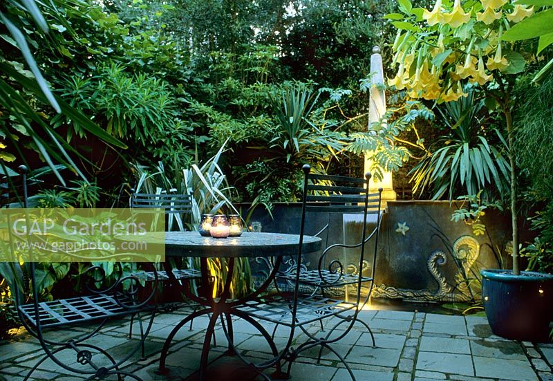 Garden lighting on terrace with metal furniture and large containers
