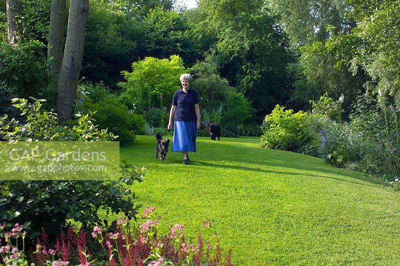 Owner, Jill Hunter walking across lawn with dogs at The Old Cornmill, Herefordshire  