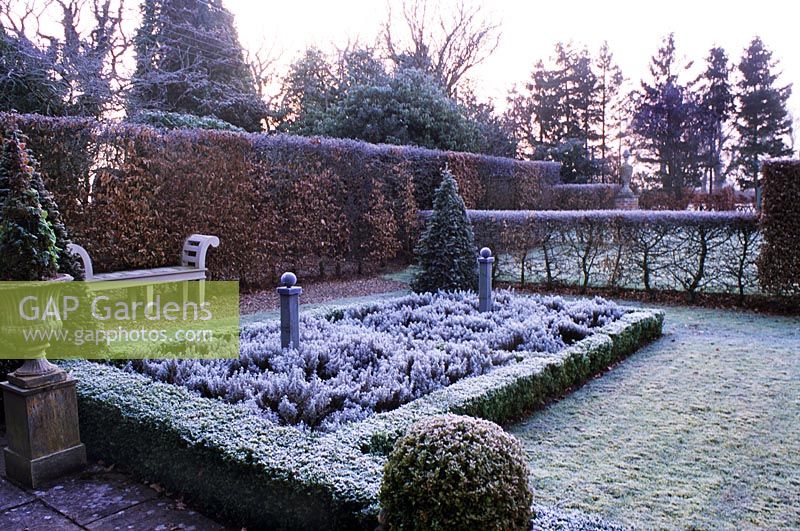 Formal parterre garden with hedge and bench in Winter frost 