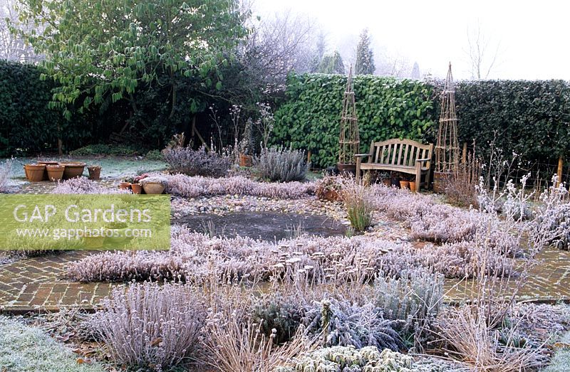 Fairfield, Surrey, garden in winter frost with circular pond and formal brick paths and bench