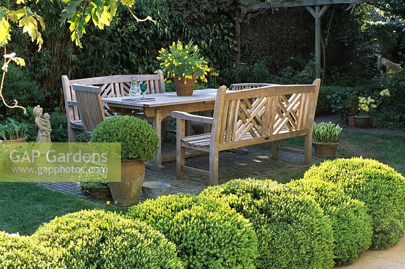 Wooden furniture on patio with topiary