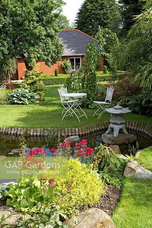 Suburban garden with pond and seating on lawn at Cypress House in Dalton