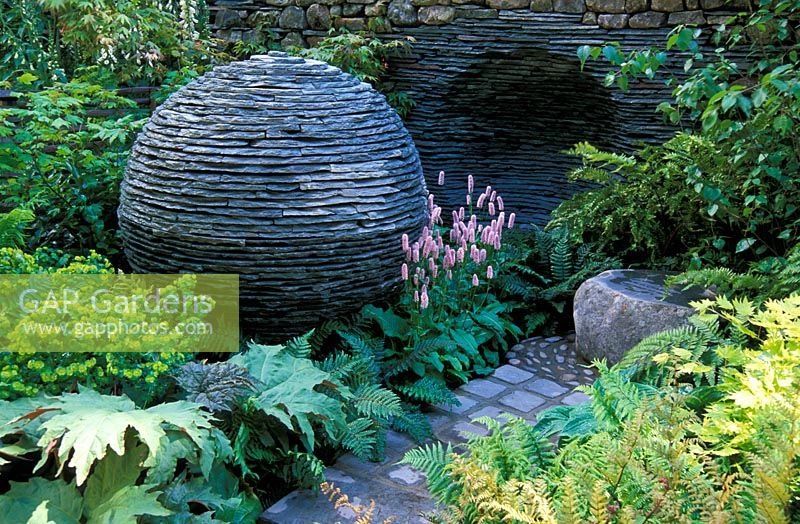 Drystone slate sphere and wall recess sculpture - Euphorbia, Rheum, Ferns, Persicaria - 'The Philosopher's Garden' at RHS Chelsea FS