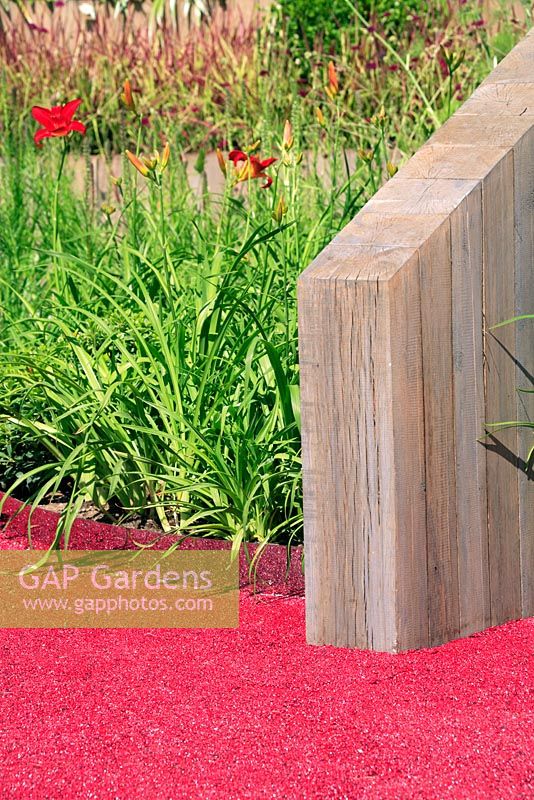 Love, Life and Regeneration garden with red aggregate path, wooden screen divide and Hemerocallis border