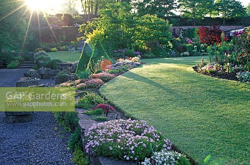 View of The Walled Garden, Holehird Gardens, Windermere, Cumbria in early morning with rays of sunlight and dew on grass