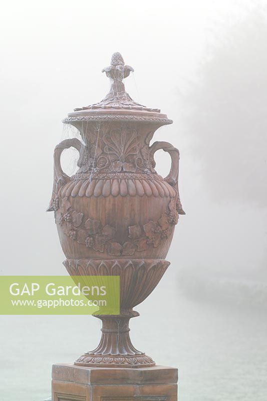 Terracotta urn with cobwebs in fog and frost