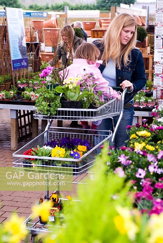 Mother and small child in plant centre with trolley selecting plants