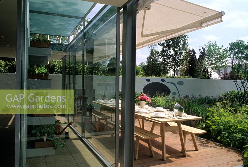 Glass garden building and decked patio area with shade canopy above