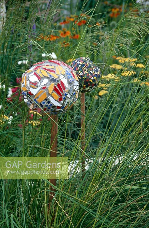 Decorative mulit-coloured mosaic balls on stakes surrounded by grasses - Crisis Garden, Hampton Court Flower Show 2005  