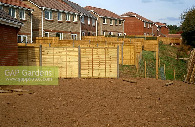 Row of newly built homes on esate in south Devon showing early stages of one of the gardens with new fences and bare soil 