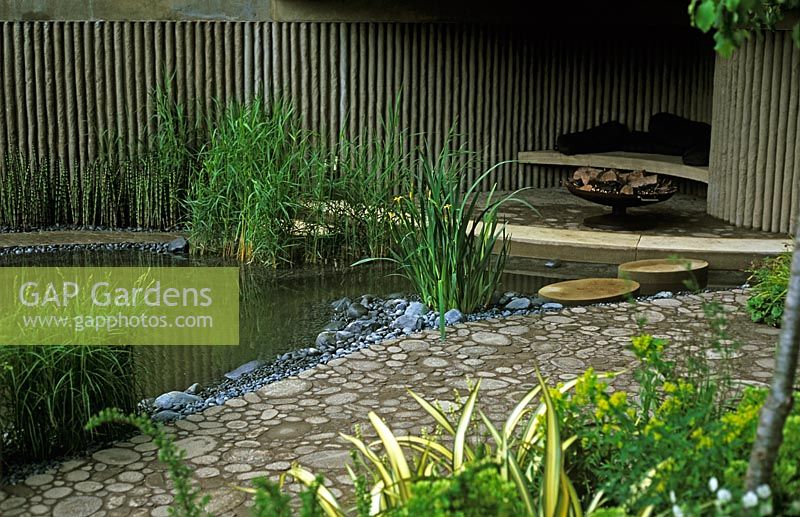Walking Barefoot With Bradstone garden at Chelsea Flower Show 2006 - Recycled paving leading to under cover seating area with modern fire brazier beside pond