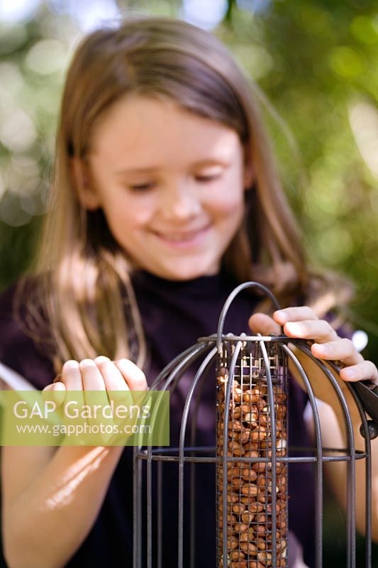 Girl filling a bird feeder with nuts