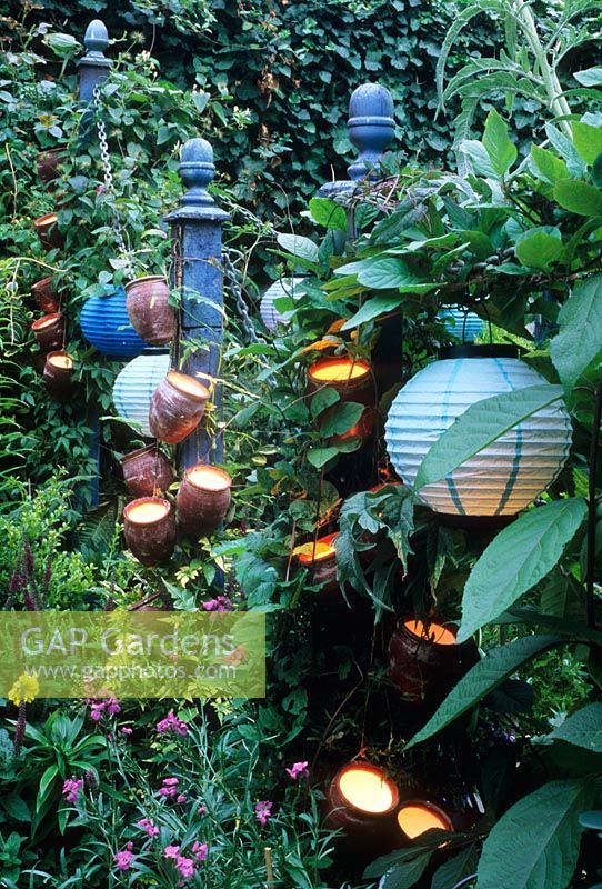 Small urban town garden - Posts adorned with containers with lights inside