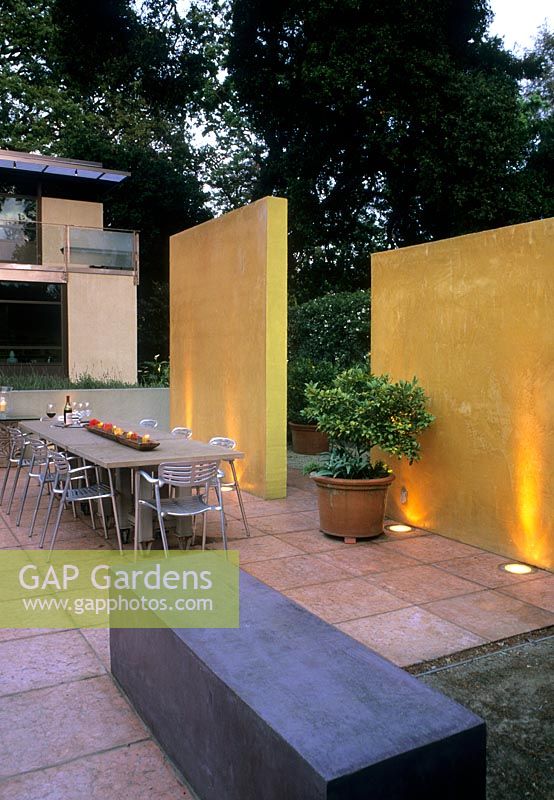 Contemporary patio with yellow wall lit by uplighters - Kuhling, USA