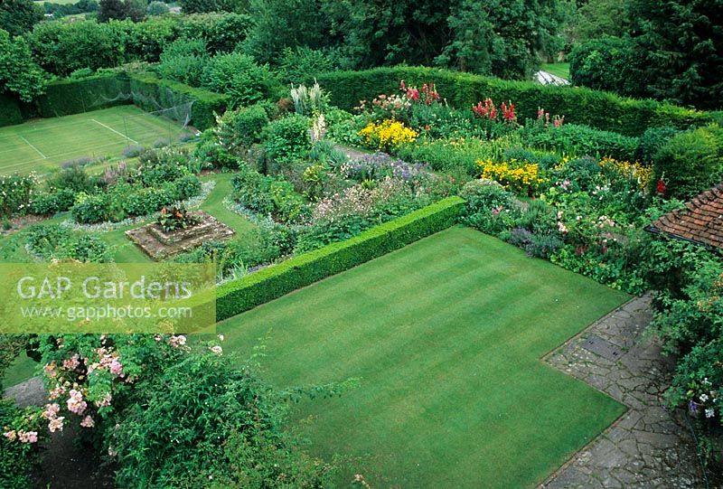 Overview of garden with lawn, dividing hedges, borders, tennis court and patio - Restored Gertrude Jeckyll Garden - Manor House, Upton Grey, Hants 



