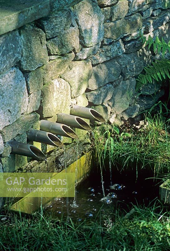 Stone wall with stainless steel pipes spouting water into pool - Therapeutic Garden for Children, MA, USA 