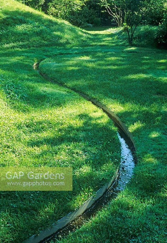 Land sculpting - Winding rill through grass in undulating garden with dips and mounds covered - The Healing Garden, Boston