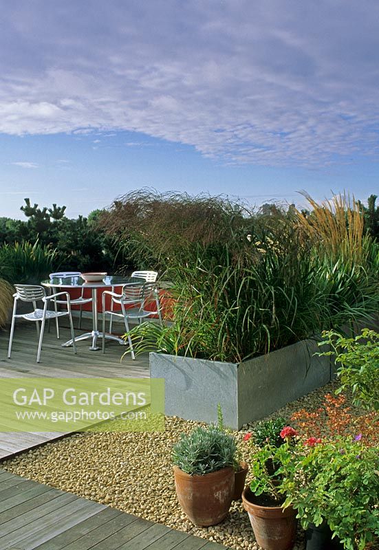 Urban contemporary roof garden with metal containers of grasses used as dividers and  bistro style table and chairs