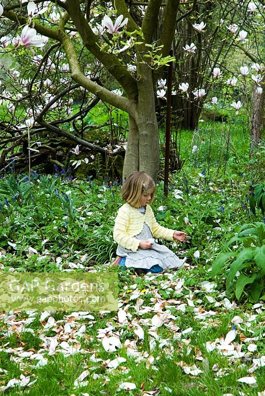 Young girl sitting under Magnolia in Spring