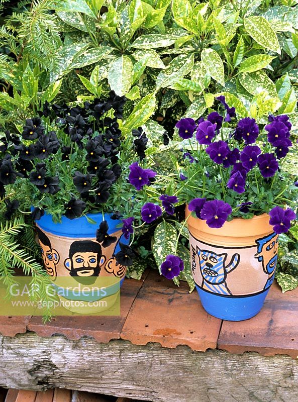 Terracotta pots planted with violas and painted with family members, including pets