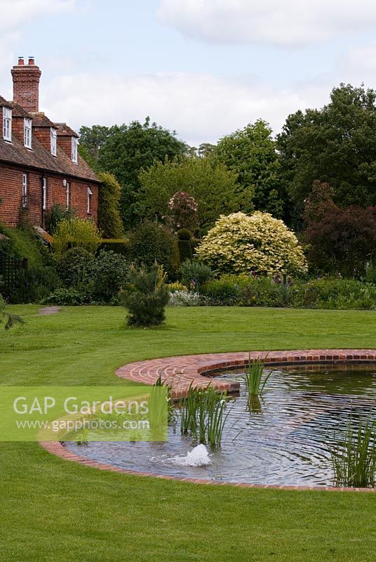 A row of brick terrace houses by a Natural Swimming Pond on the edge of the Wimpole Hall Estate, Cambridgeshire