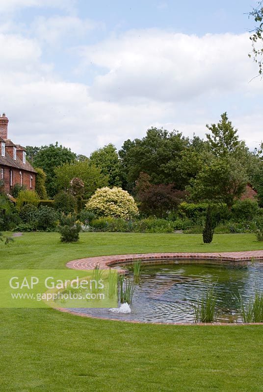 Natural Swimming Pond with a row of brick terrace houses on the edge of the Wimpole Hall Estate, Cambridgeshire