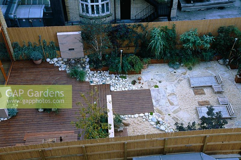 View onto roof garden with gravel, bamboo, loungers, red cedar decking and letter box fountain 