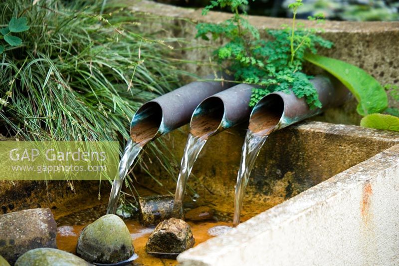 Water feature with three pipes spilling water into a rill at Wingwell nursery,  Rutland