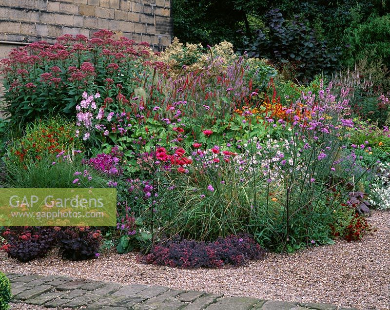 Colourful herbaceous perennial border in gravel next to path at Mayroyd Mill House, Yorkshire. Design Richard Easton and Steve Mackay. 