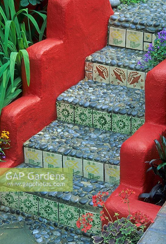Red painted low walls of steps with pebble treads and tiled risers. Mediterranean Moorish style tiles and decorative pebbles - Brighton